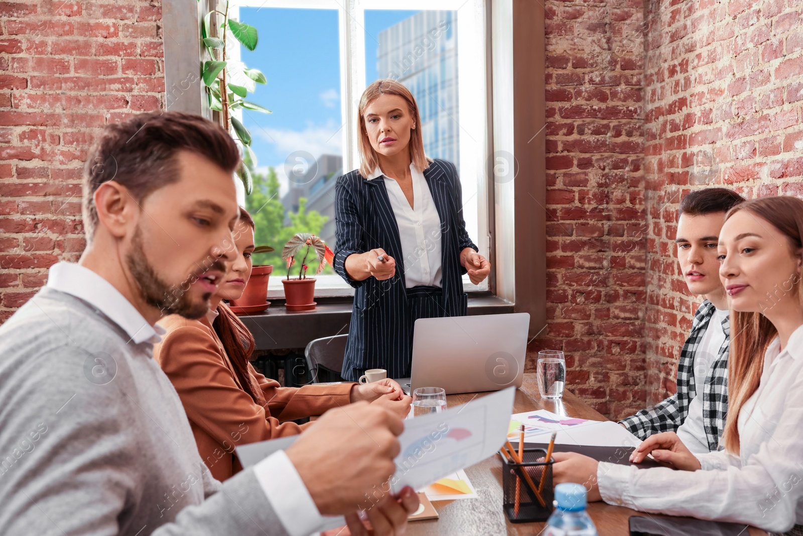 Photo of Businesswoman having meeting with her employees in office. Lady boss