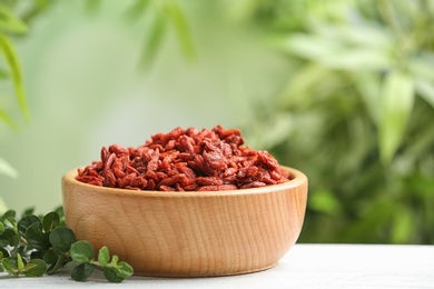 Photo of Bowl of dried goji berries on table against blurred background. Space for text