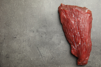 Photo of Fresh raw beef steak on grey table, top view. Space for text