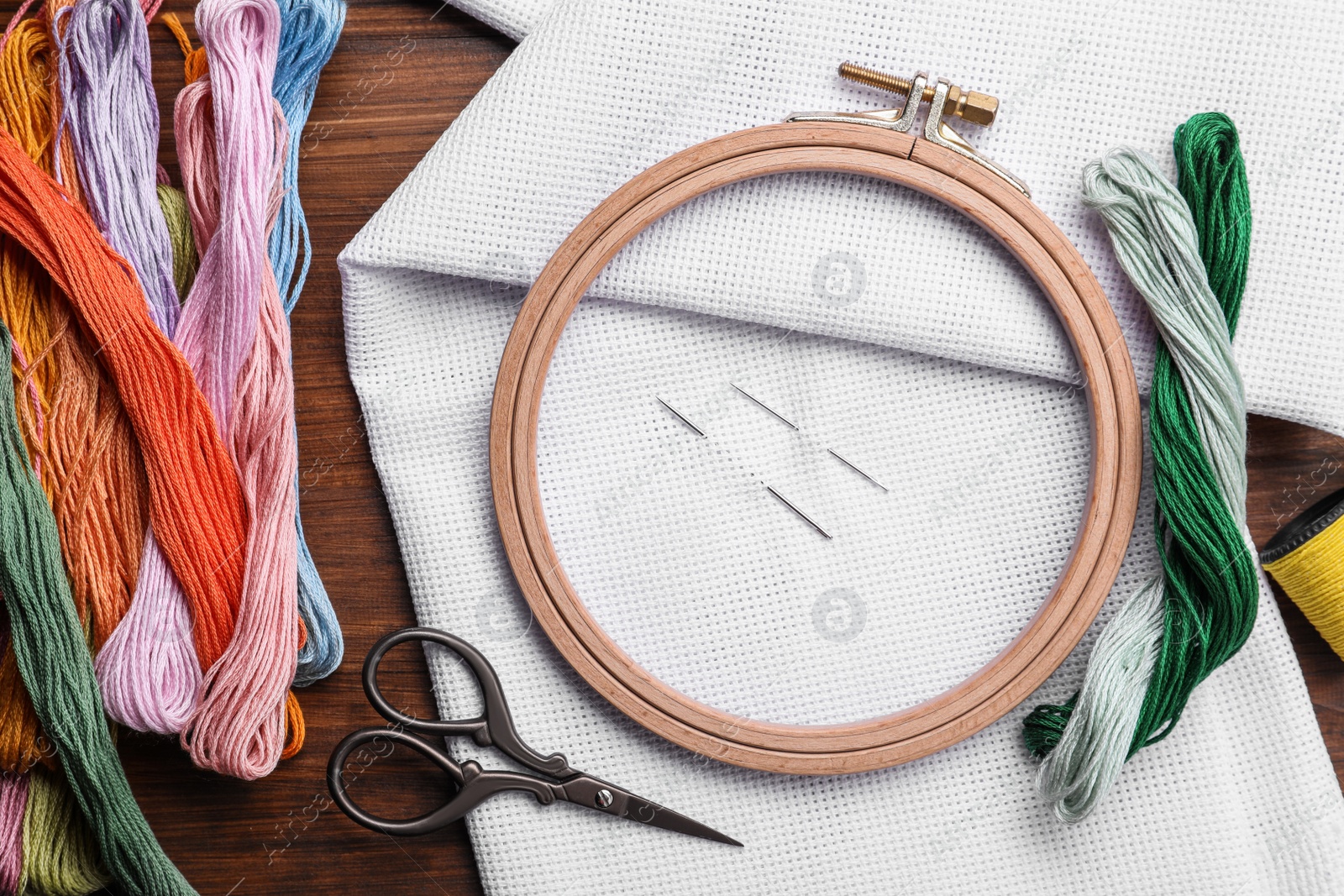 Photo of Set of embroidery equipment on wooden table, flat lay