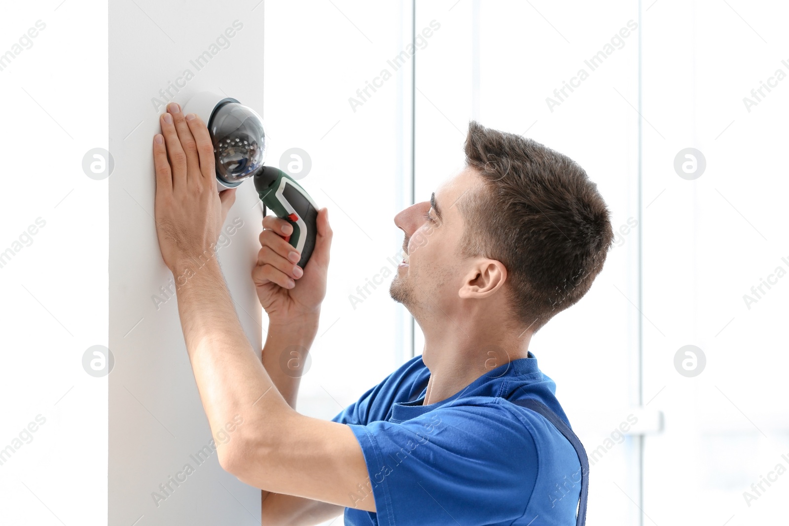 Photo of Technician installing CCTV camera on wall indoors