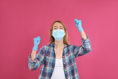 Photo of Emotional woman with protective mask and gloves on pink background. Strong immunity concept