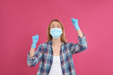 Emotional woman with protective mask and gloves on pink background. Strong immunity concept