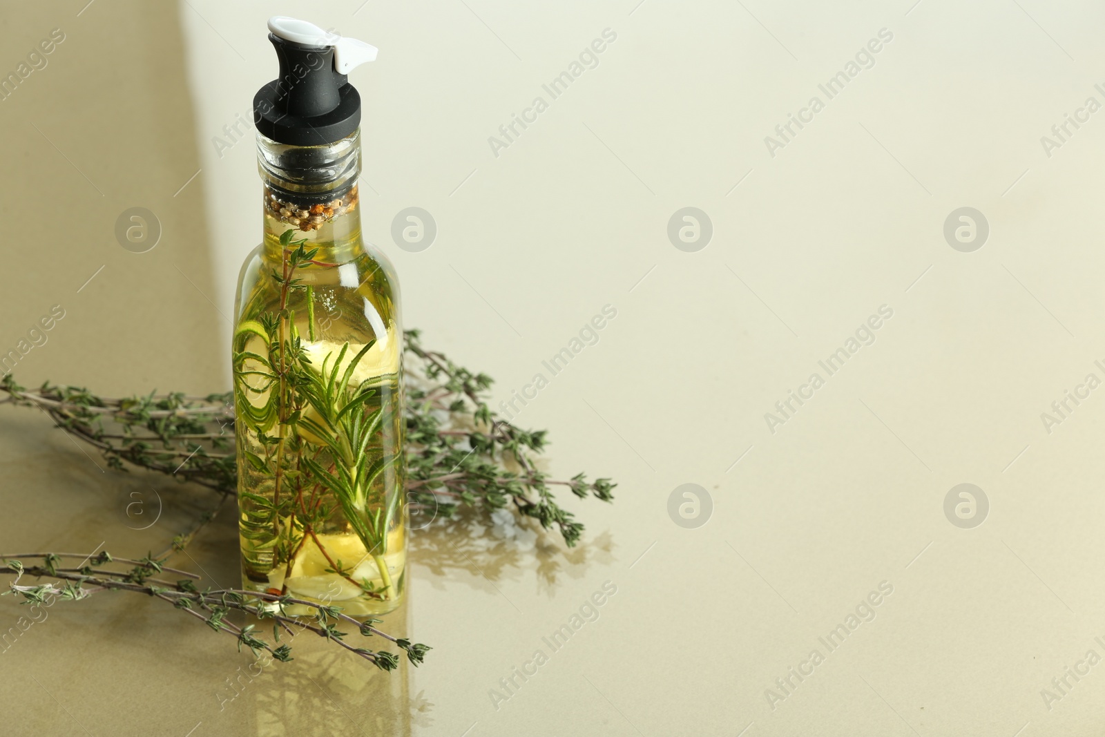 Photo of Cooking oil with spices and herbs in bottle on colorful table. Space for text