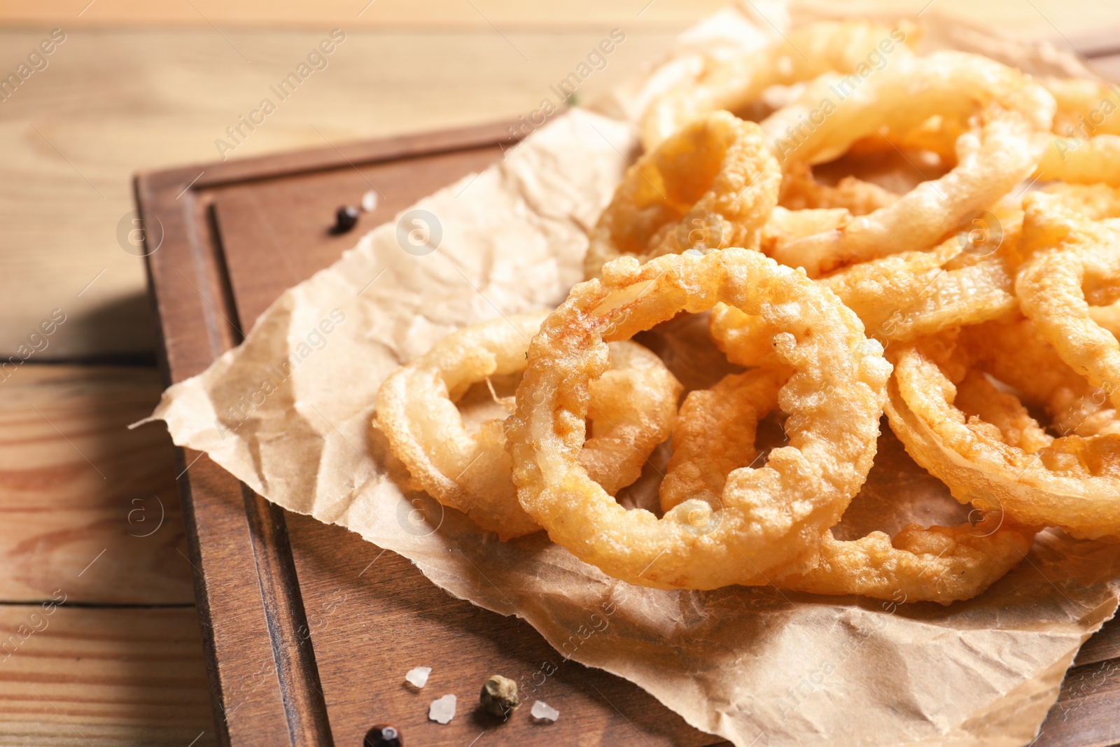 Photo of Homemade crunchy fried onion rings on wooden board, closeup