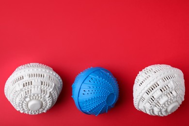 Photo of Laundry dryer balls on red background, flat lay. Space for text