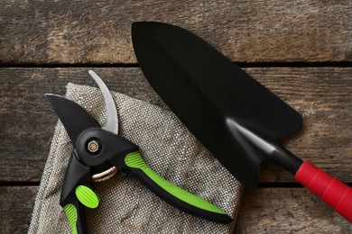 Secateurs and shovel on wooden table, flat lay