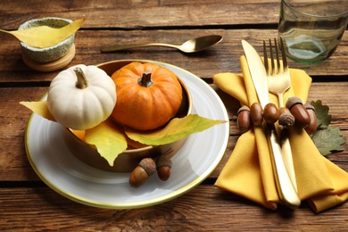 Photo of Seasonal table setting with pumpkins and other autumn decor on wooden background