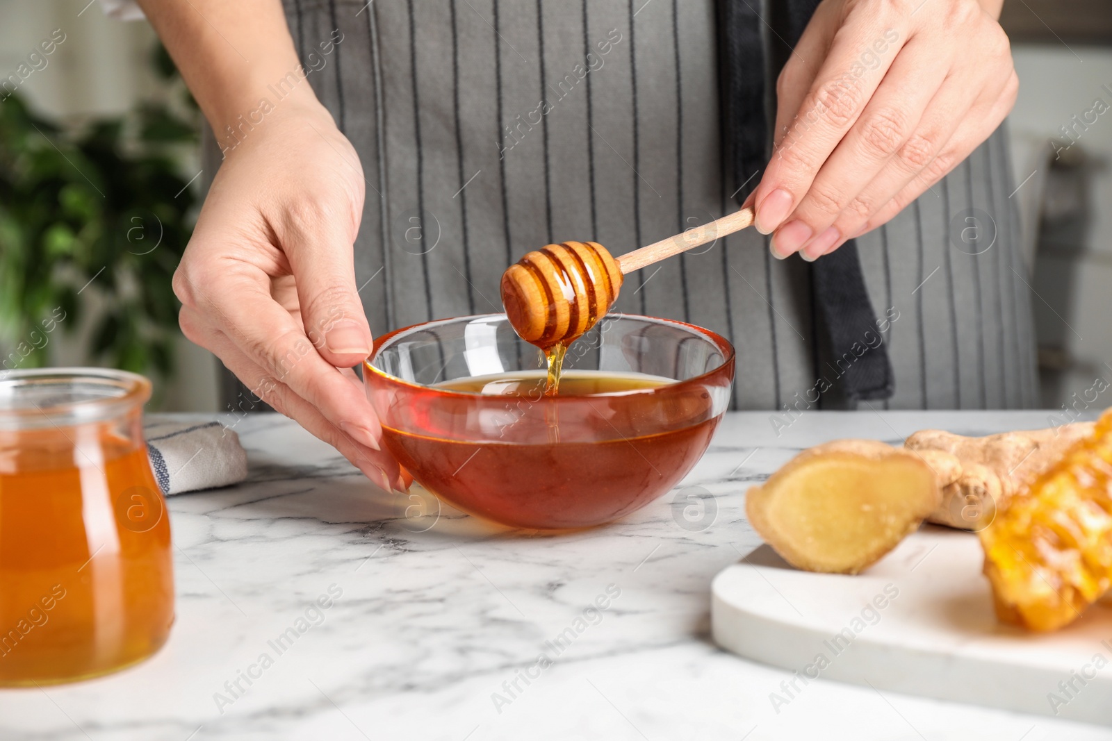 Photo of Woman with tasty honey at marble table, closeup