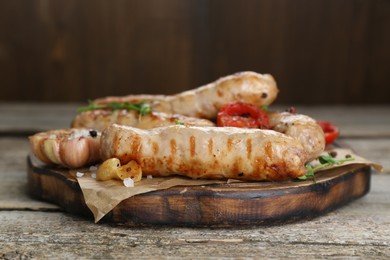 Photo of Tasty fresh grilled sausages with vegetables on wooden table, closeup
