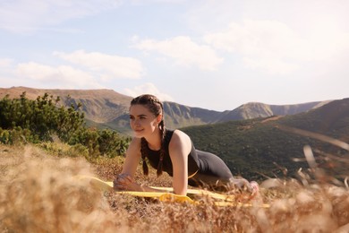Image of Beautiful young woman doing yoga in mountains on sunny morning