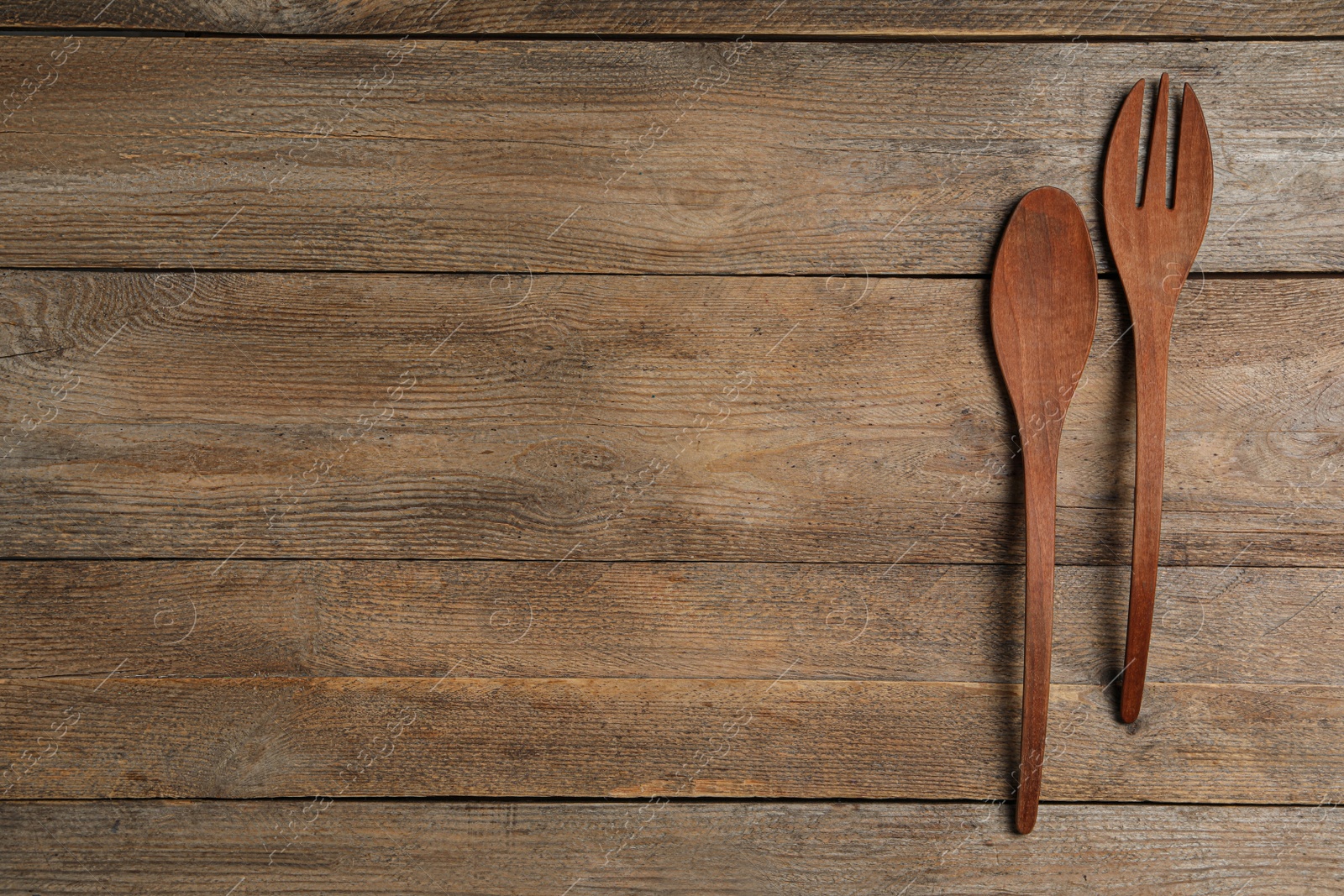 Photo of Fork and spoon on wooden table, flat lay with space for text. Cooking utensils