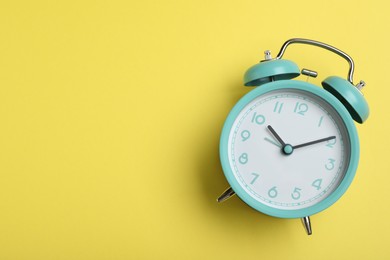 Photo of Alarm clock on yellow background, top view with space for text. School time