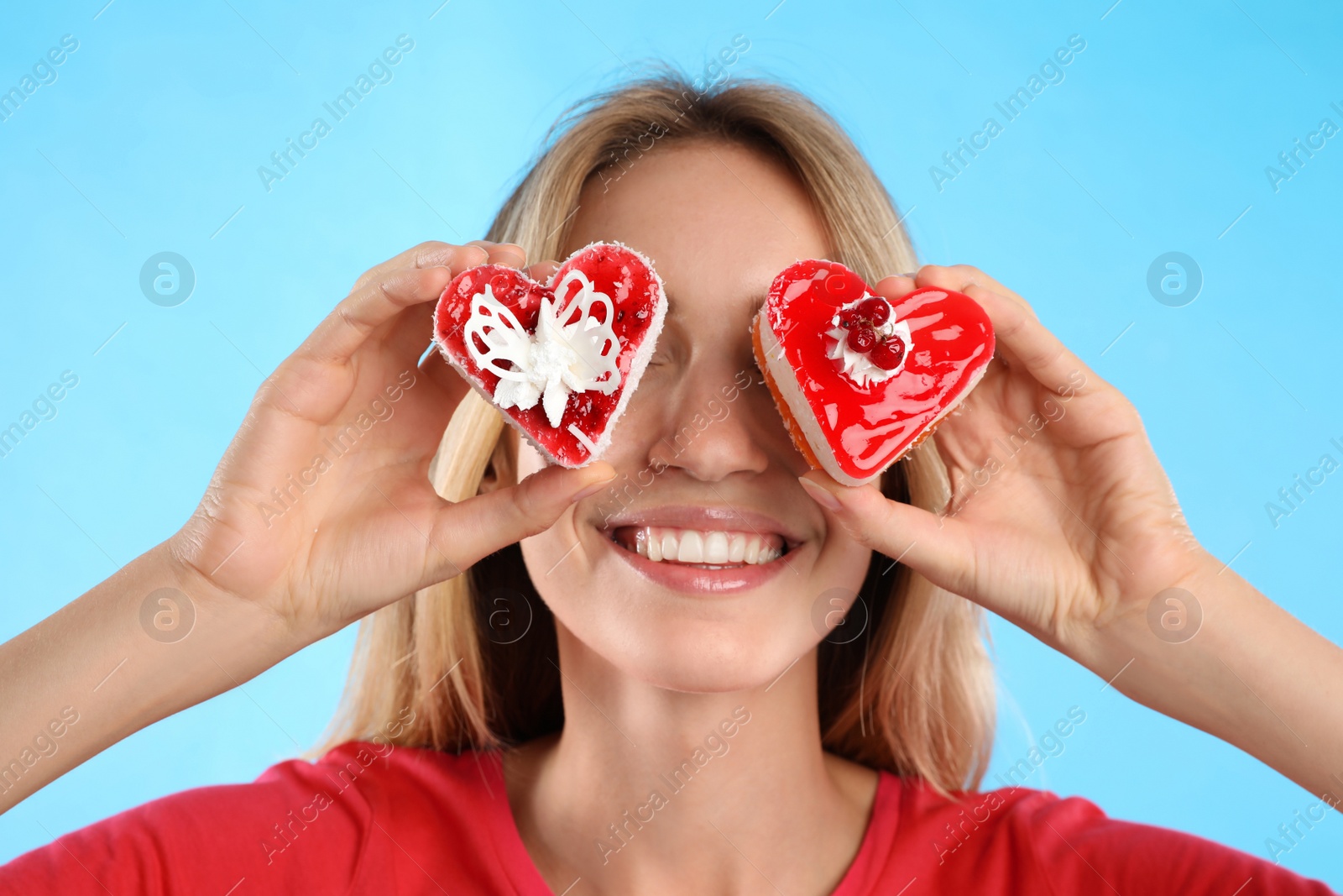 Photo of Concept of choice between healthy and junk food. Woman with cakes on light blue background