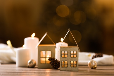 Photo of Composition with house shaped candle holder on wooden table against blurred background. Christmas decoration