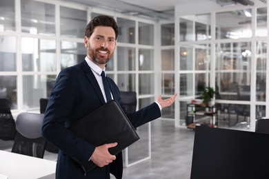 Happy real estate agent with leather portfolio in office