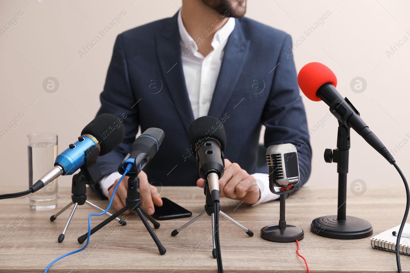 Photo of Businessman giving interview at table with microphones, closeup. Journalist conference