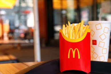 Photo of MYKOLAIV, UKRAINE - AUGUST 11, 2021: Big portion of McDonald's French fries and drink on table in cafe. Space for text