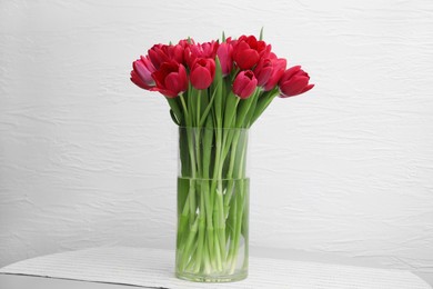 Photo of Bouquet of beautiful tulips in glass vase on table indoors