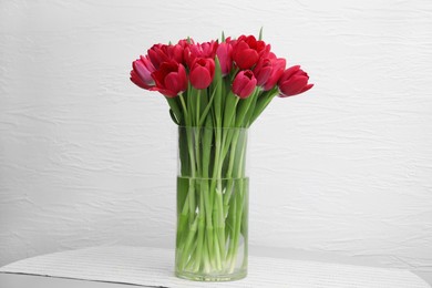 Bouquet of beautiful tulips in glass vase on table indoors