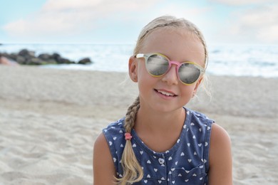 Photo of Little girl wearing sunglasses at beach on sunny day. Space for text