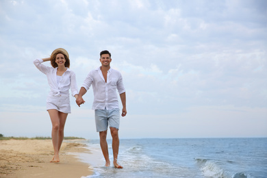 Happy couple having romantic walk on beach. Space for text