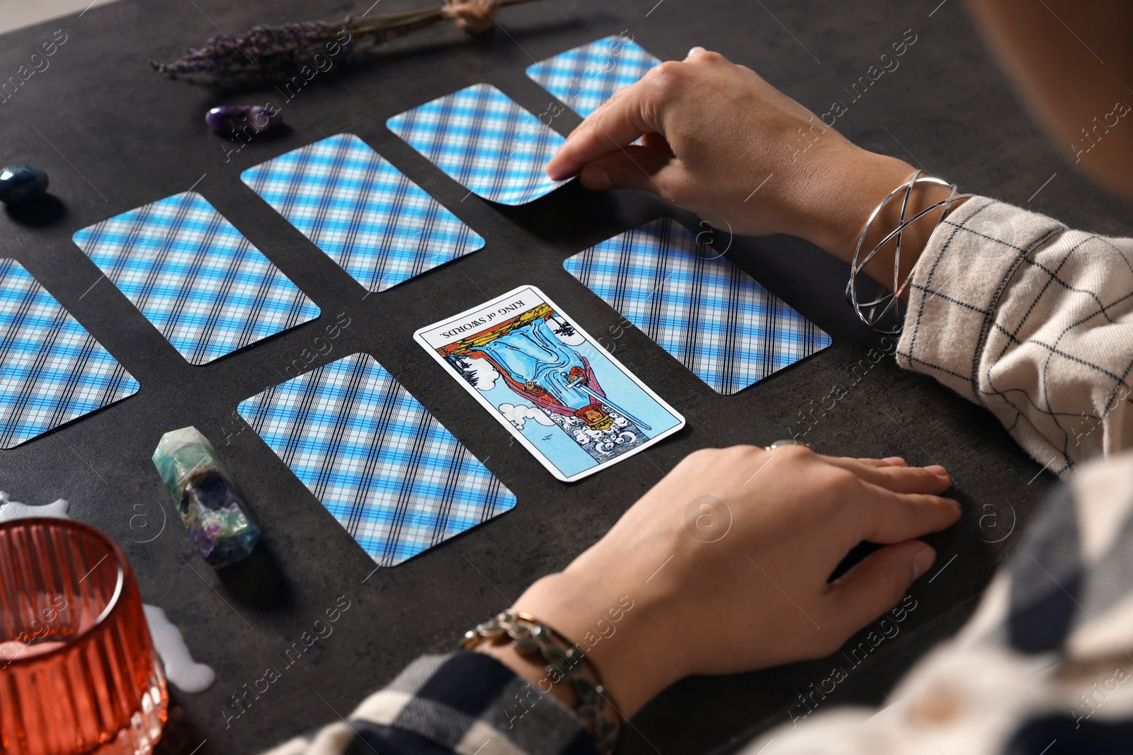 Photo of Fortune teller predicting future on spread of tarot cards at grey table, closeup