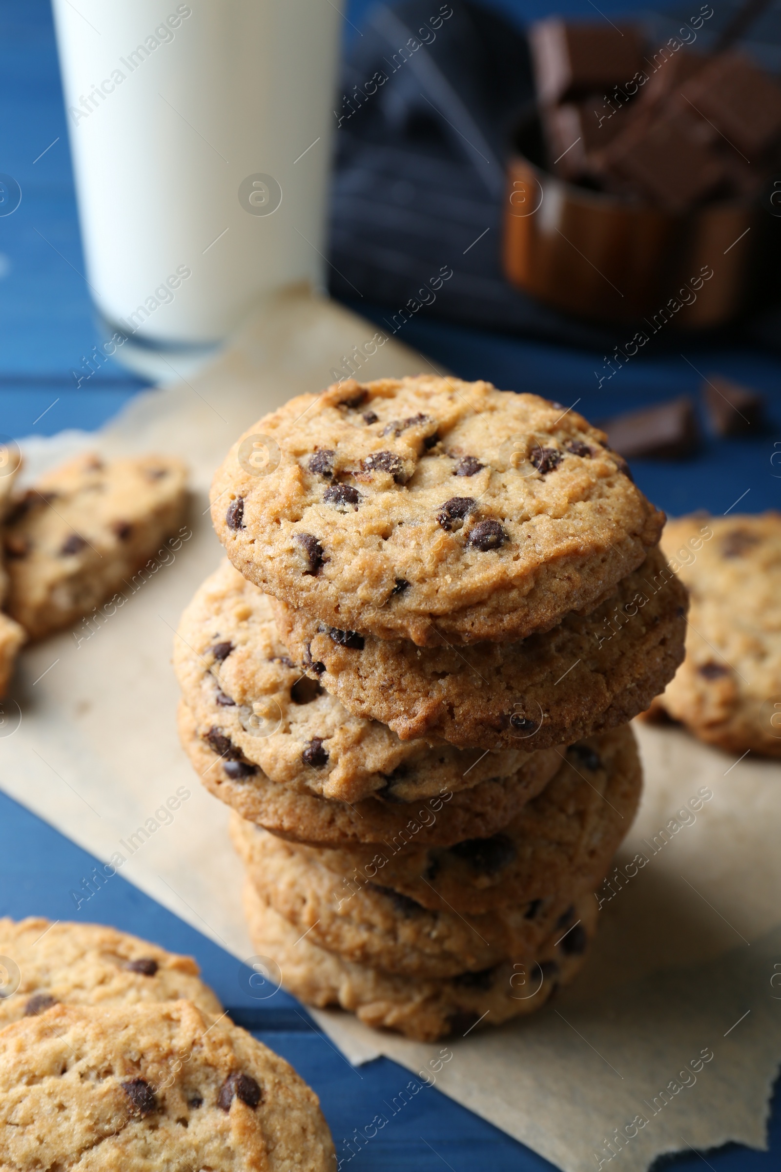 Photo of Tasty chocolate chip cookies and glass of milk on blue wooden table, closeup