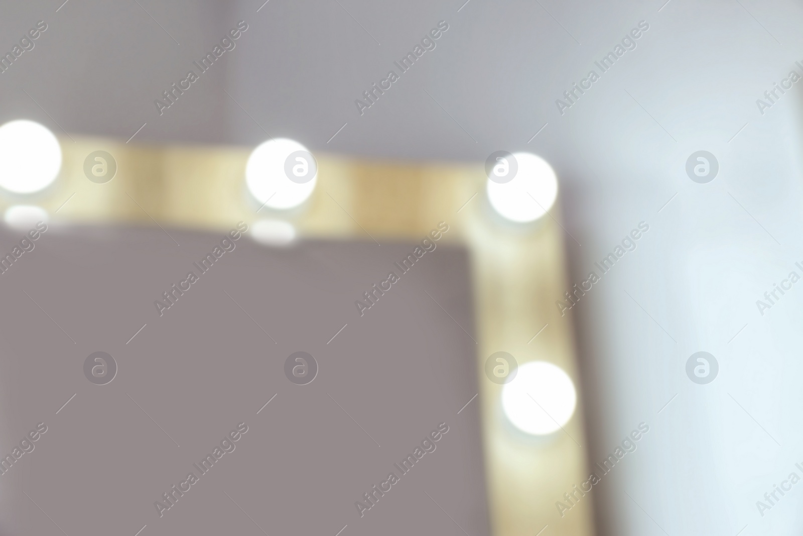 Photo of Blurred view of makeup mirror near white wall in dressing room