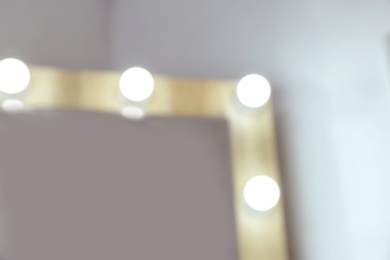 Blurred view of makeup mirror near white wall in dressing room