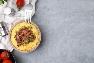 Photo of Cooked cornmeal with bacon and microgreens in bowl on light grey table, top view. Space for text