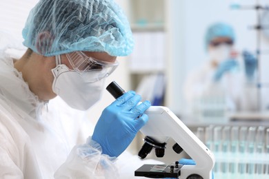 Photo of Scientist working with samples and microscope in laboratory