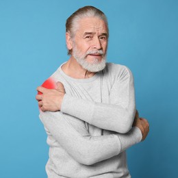 Image of Senior man suffering from rheumatism on light blue background