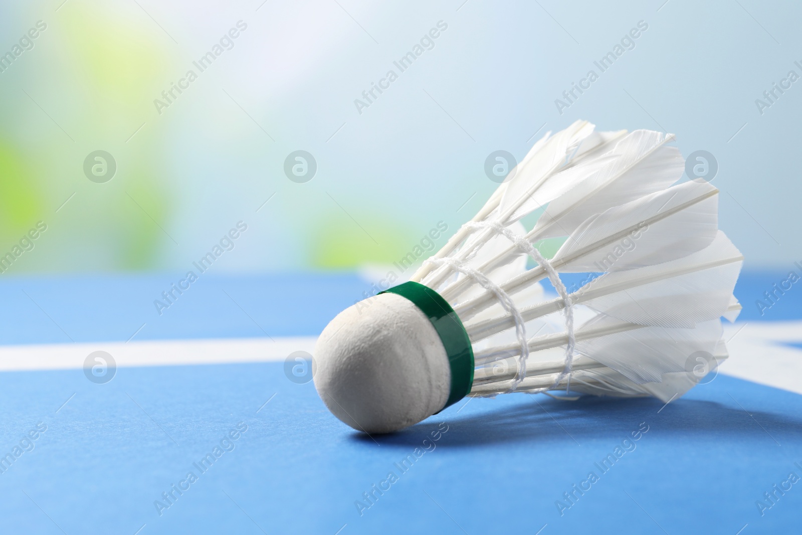 Photo of Feather badminton shuttlecock on blue table against blurred background, closeup. Space for text