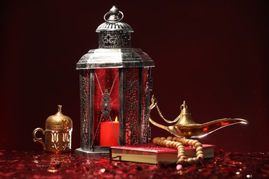 Arabic lantern, Quran, misbaha and Aladdin magic lamp on shiny red table