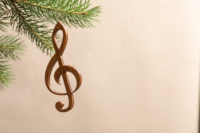 Fir tree branch with wooden treble clef on blurred background. Christmas music concept