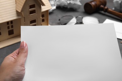 Photo of Woman holding last will and testament at grey table, closeup