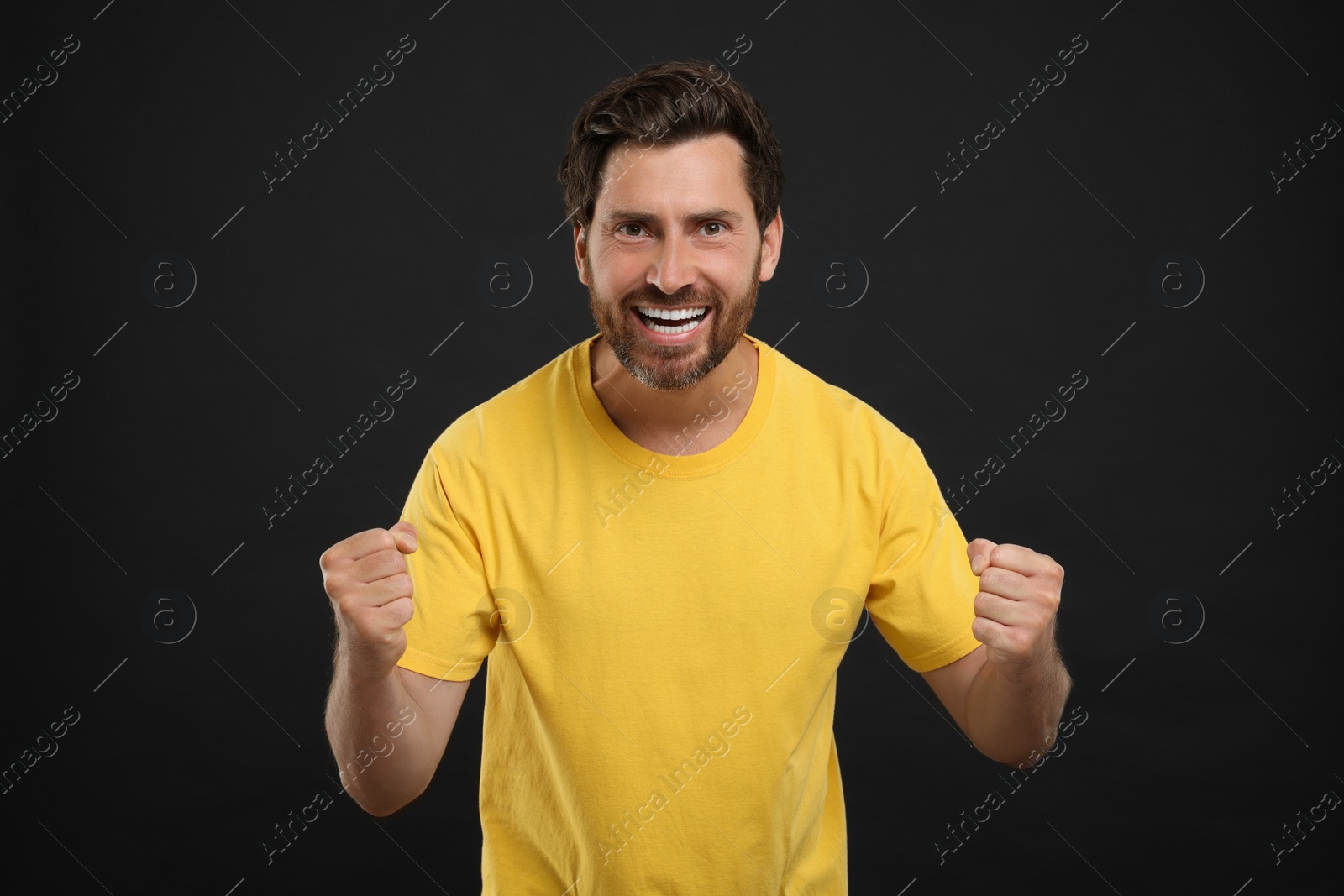 Photo of Emotional sports fan celebrating on black background