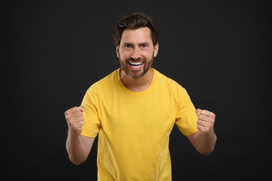 Photo of Emotional sports fan celebrating on black background