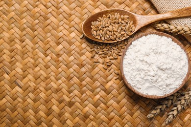 Photo of Wheat flour in bowl, spikes and grains on wicker mat, flat lay. Space for text