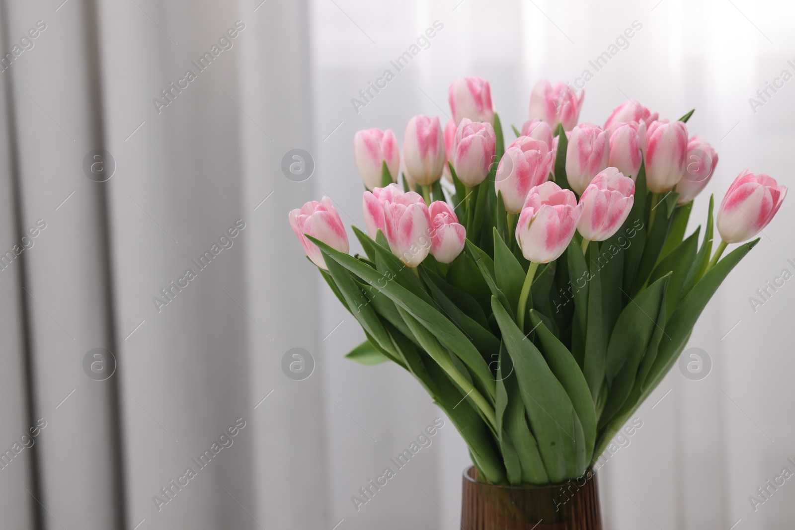 Photo of Beautiful bouquet of fresh pink tulips indoors. Space for text