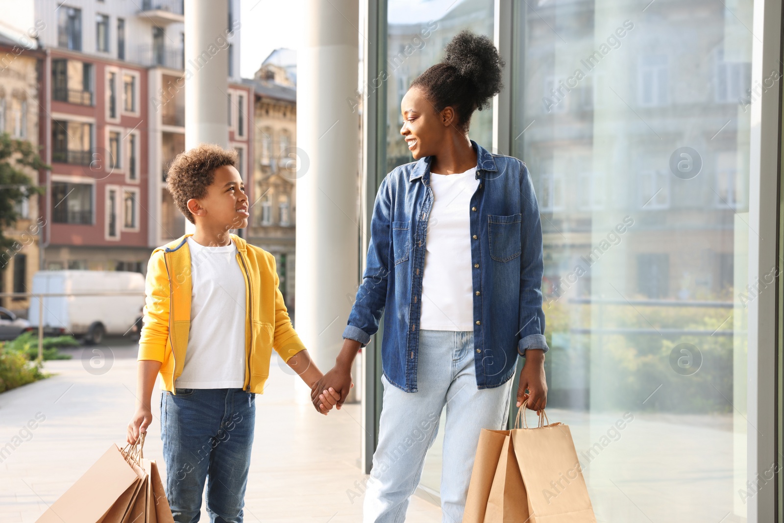 Photo of Family shopping. Happy mother and son with purchases near mall outdoors