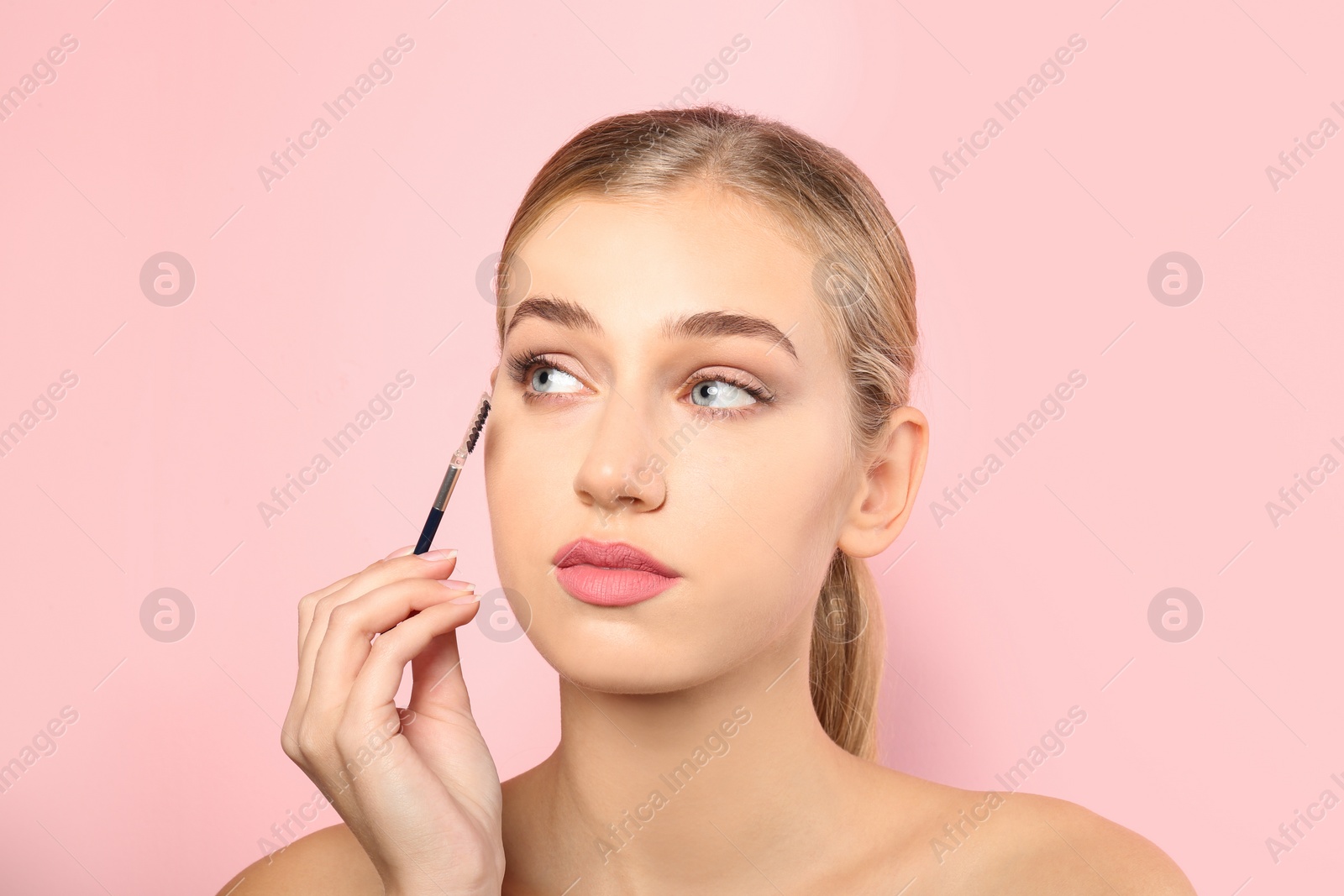 Photo of Portrait of young woman with beautiful natural eyelashes holding brush on color background