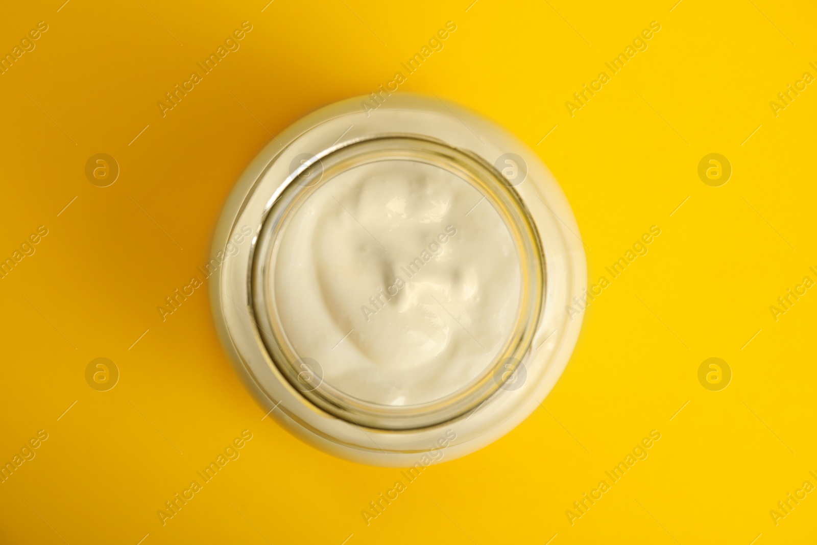 Photo of Tasty organic yogurt on yellow background, top view