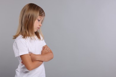 Photo of Resentful girl with crossed arms on grey background. Space for text