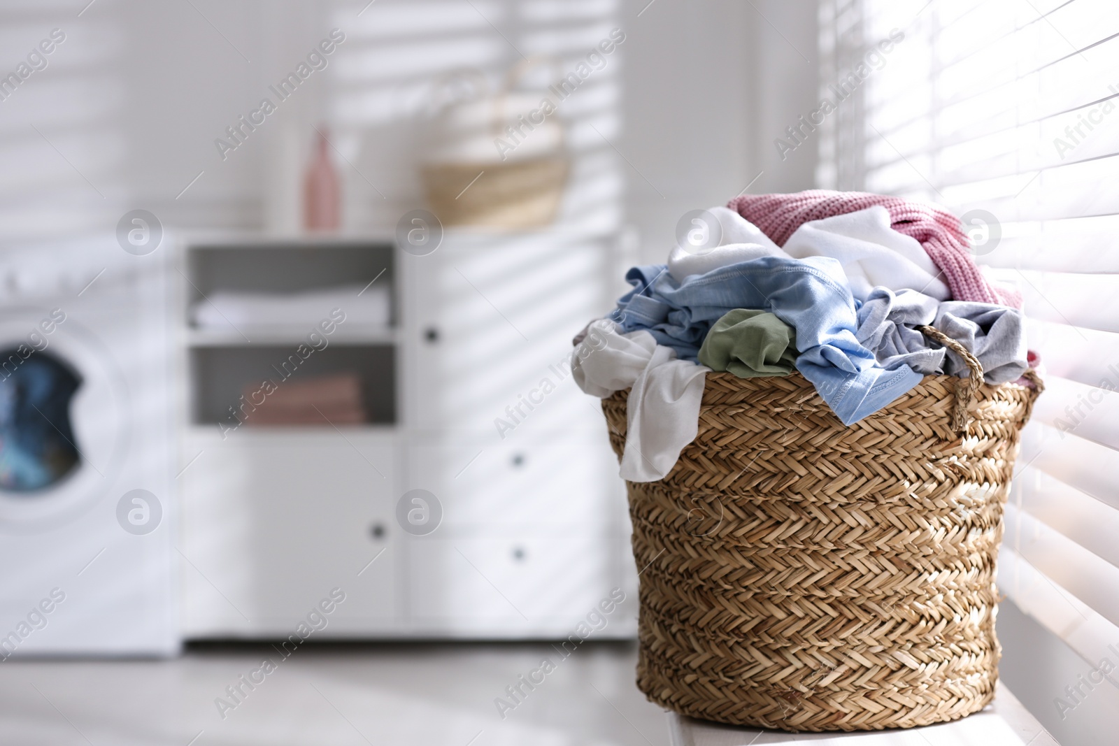 Photo of Wicker basket with dirty laundry on window sill indoors, space for text