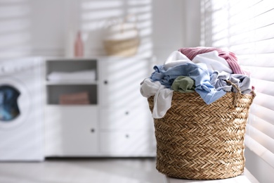 Photo of Wicker basket with dirty laundry on window sill indoors, space for text