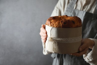 Photo of Woman holding delicious Panettone cake on grey background, closeup with space for text. Traditional Italian pastry