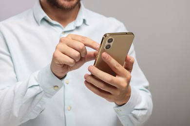 Photo of Man sending message via smartphone on grey background, closeup