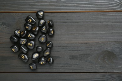 Photo of Pile of rune stones on black wooden table, flat lay